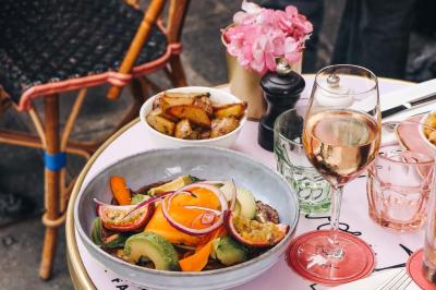 Assiette de sandwichs triangulaires et planche de pizza garnie de mozzarella et tomates, avec verres de vin rouge.