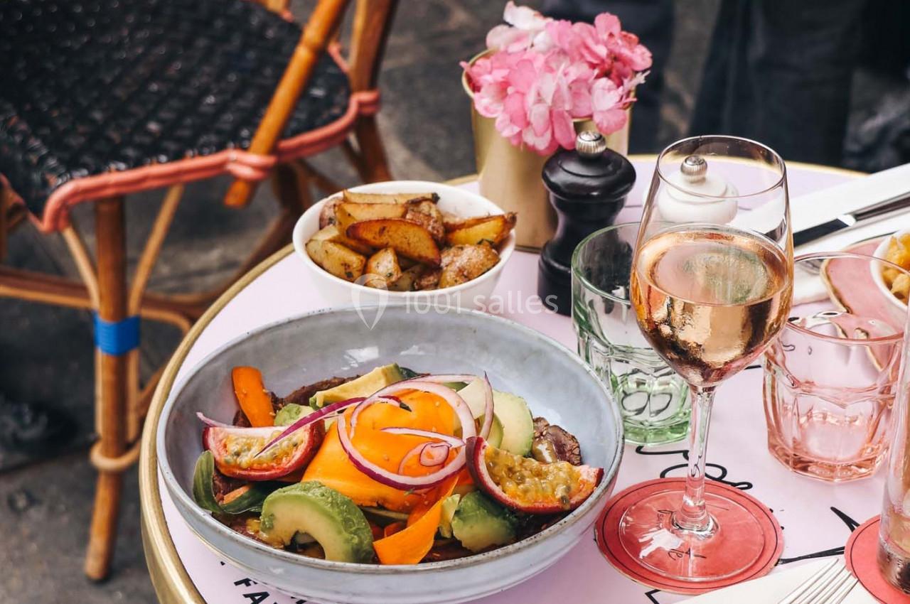 Assiette de légumes frais avec un verre de vin rosé sur une table de café en extérieur, accompagnée de pommes de terre…