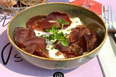 Assiette de sandwichs triangulaires et planche de pizza garnie de mozzarella et tomates, avec verres de vin rouge.