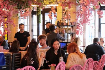 Assiette de sandwichs triangulaires et planche de pizza garnie de mozzarella et tomates, avec verres de vin rouge.