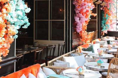 Étagères en bois remplies de bouteilles d'alcool, encadrées de briques et de feuillage, dans un décor de bar chaleureux.
