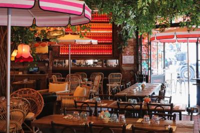 Étagères en bois remplies de bouteilles d'alcool, encadrées de briques et de feuillage, dans un décor de bar chaleureux.