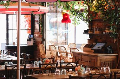 Étagères en bois remplies de bouteilles d'alcool, encadrées de briques et de feuillage, dans un décor de bar chaleureux.