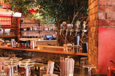 Étagères en bois remplies de bouteilles d'alcool, encadrées de briques et de feuillage, dans un décor de bar chaleureux.