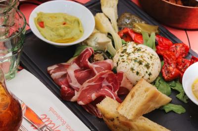 Étagères en bois remplies de bouteilles d'alcool, encadrées de briques et de feuillage, dans un décor de bar chaleureux.