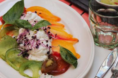 Étagères en bois remplies de bouteilles d'alcool, encadrées de briques et de feuillage, dans un décor de bar chaleureux.