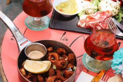Étagères en bois remplies de bouteilles d'alcool, encadrées de briques et de feuillage, dans un décor de bar chaleureux.