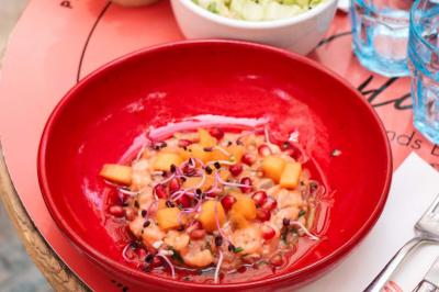 Étagères en bois remplies de bouteilles d'alcool, encadrées de briques et de feuillage, dans un décor de bar chaleureux.
