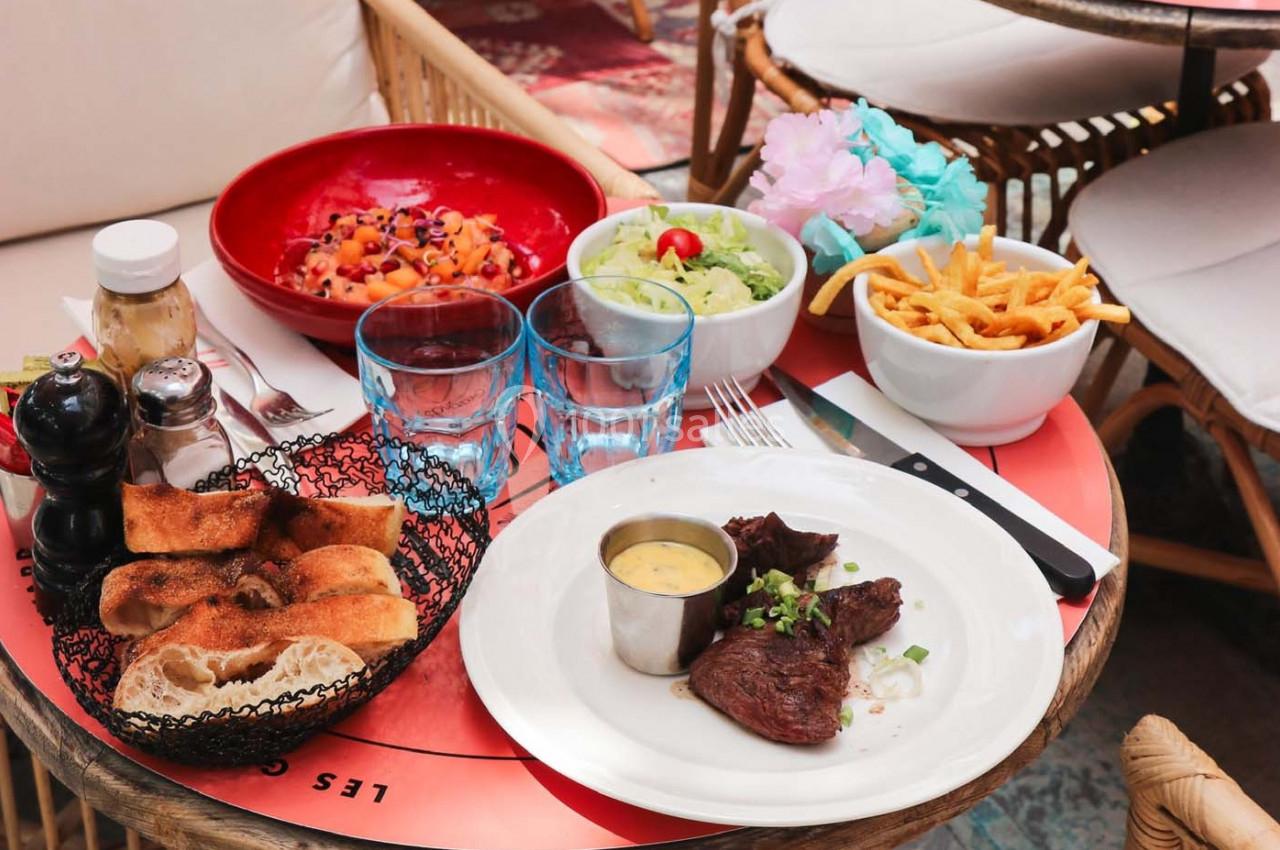 Assiette de viande avec sauce, accompagnée de frites, salade, pain et dessert, servie sur une table de restaurant.