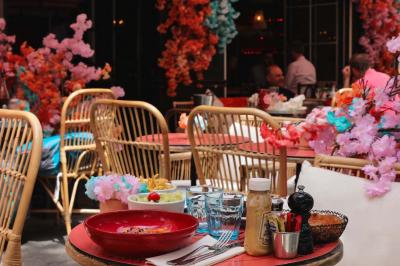 Étagères en bois remplies de bouteilles d'alcool, encadrées de briques et de feuillage, dans un décor de bar chaleureux.