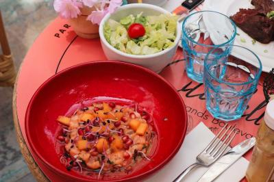 Étagères en bois remplies de bouteilles d'alcool, encadrées de briques et de feuillage, dans un décor de bar chaleureux.