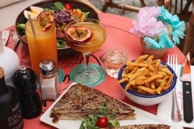 Étagères en bois remplies de bouteilles d'alcool, encadrées de briques et de feuillage, dans un décor de bar chaleureux.