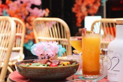 Étagères en bois remplies de bouteilles d'alcool, encadrées de briques et de feuillage, dans un décor de bar chaleureux.