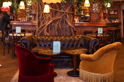 Étagères en bois remplies de bouteilles d'alcool, encadrées de briques et de feuillage, dans un décor de bar chaleureux.