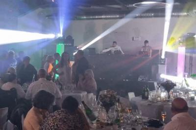 Salle décorée pour une fête, éclairée de lumières violettes, avec des ballons rouges et un chiffre ’18’ en ballons.