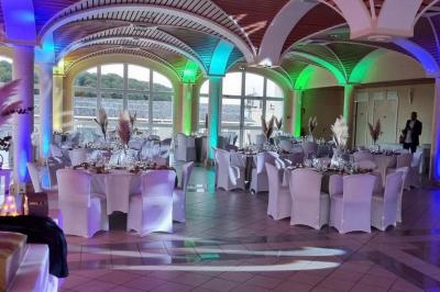 Salle décorée pour une fête, éclairée de lumières violettes, avec des ballons rouges et un chiffre ’18’ en ballons.