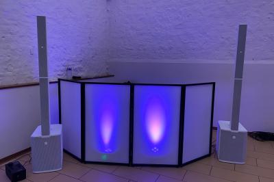 Salle décorée pour une fête, éclairée de lumières violettes, avec des ballons rouges et un chiffre ’18’ en ballons.