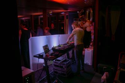 Salle décorée pour une fête, éclairée de lumières violettes, avec des ballons rouges et un chiffre ’18’ en ballons.