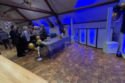 Salle décorée pour une fête, éclairée de lumières violettes, avec des ballons rouges et un chiffre ’18’ en ballons.