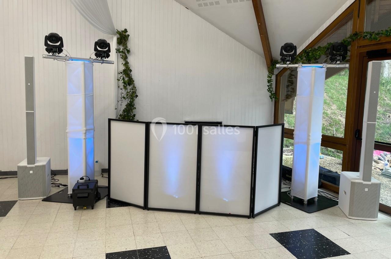Installation de matériel de sonorisation et d'éclairage dans une salle avec des colonnes lumineuses et une table de mixage.