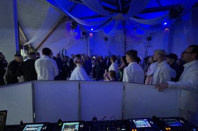 Salle décorée pour une fête, éclairée de lumières violettes, avec des ballons rouges et un chiffre ’18’ en ballons.