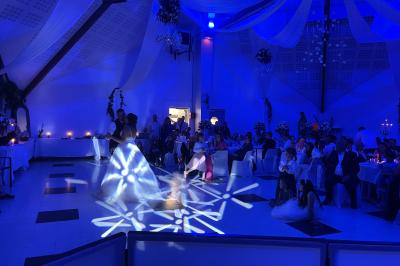 Salle décorée pour une fête, éclairée de lumières violettes, avec des ballons rouges et un chiffre ’18’ en ballons.