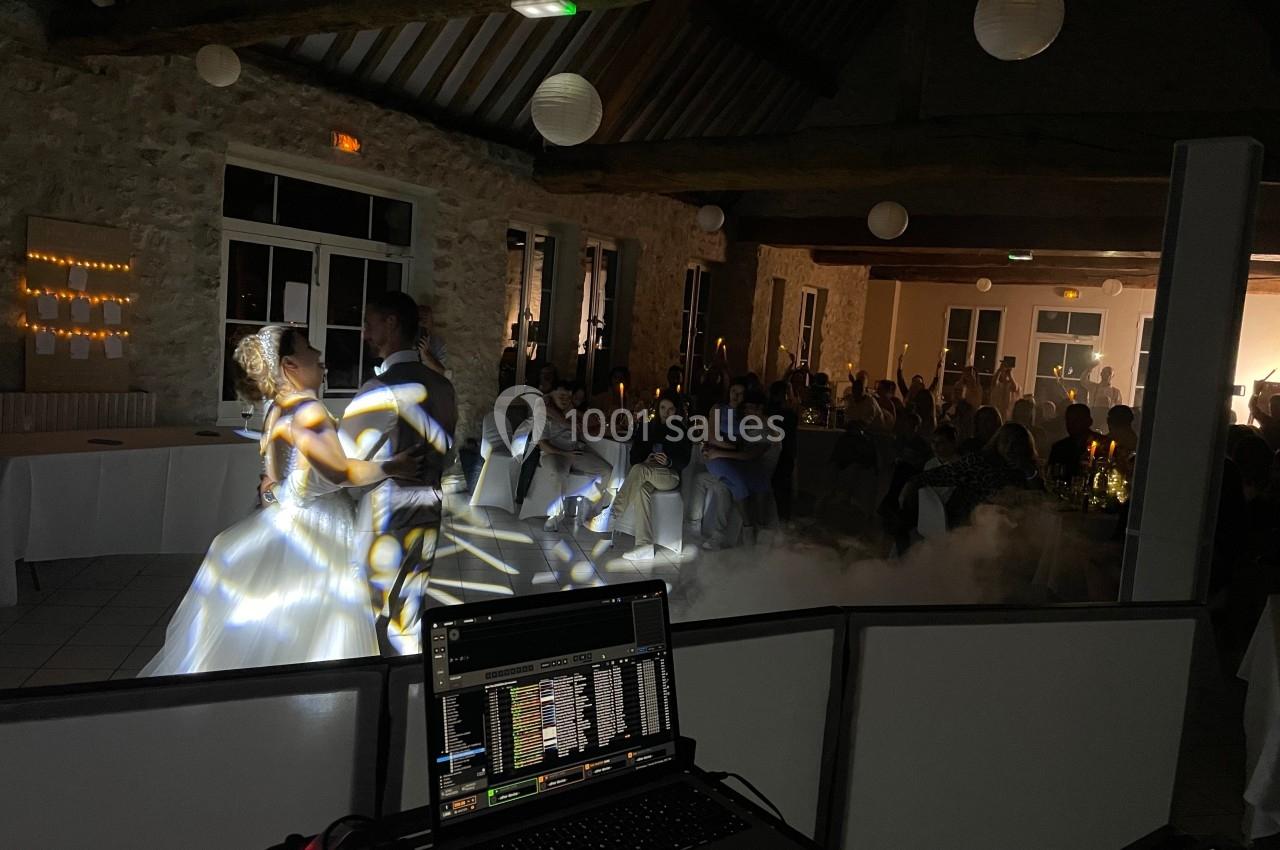 Un couple danse dans une salle en pierre éclairée, entouré d'invités assis, avec un éclairage et une ambiance festive.