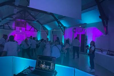 Salle décorée pour une fête, éclairée de lumières violettes, avec des ballons rouges et un chiffre ’18’ en ballons.