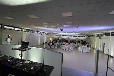 Salle décorée pour une fête, éclairée de lumières violettes, avec des ballons rouges et un chiffre ’18’ en ballons.