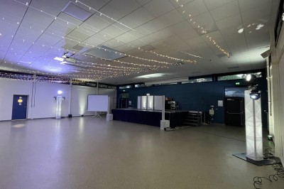 Salle décorée pour une fête, éclairée de lumières violettes, avec des ballons rouges et un chiffre ’18’ en ballons.
