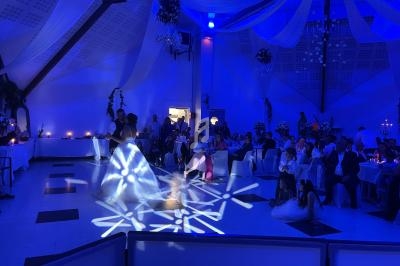 Un couple danse au centre d'une salle de réception éclairée en bleu, entouré d'invités assis.