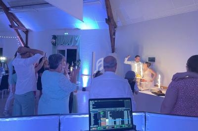 Un groupe de personnes regarde un homme souffler des bougies sur un gâteau dans une salle éclairée en bleu.