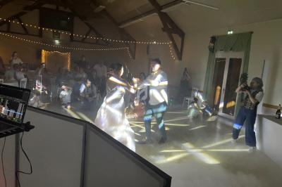 Un couple danse sous des jeux de lumière dans une salle décorée, entouré d'invités assis et debout.