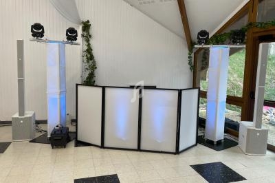 Installation de matériel de sonorisation et d'éclairage dans une salle avec des colonnes lumineuses et une table de mixage.