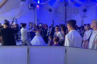 Groupe de personnes dansant lors d'une réception dans une salle décorée avec des drapés et un éclairage bleu.