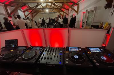 Salle décorée pour une fête avec éclairage violet, ballons rouges formant le chiffre 18 et espace de danse dégagé.