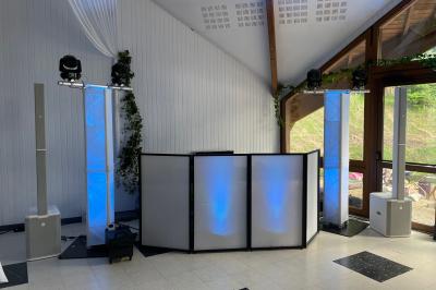 Salle décorée pour une fête avec éclairage violet, ballons rouges formant le chiffre 18 et espace de danse dégagé.