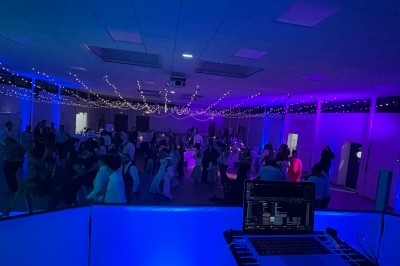 Salle décorée pour une fête avec éclairage violet, ballons rouges formant le chiffre 18 et espace de danse dégagé.