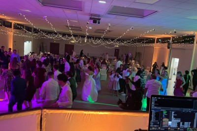 Salle décorée pour une fête avec éclairage violet, ballons rouges formant le chiffre 18 et espace de danse dégagé.