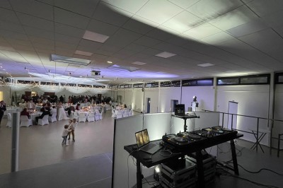 Salle décorée pour une fête avec éclairage violet, ballons rouges formant le chiffre 18 et espace de danse dégagé.