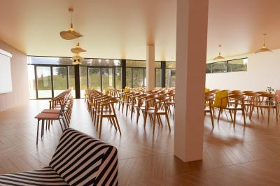 Chambre lumineuse avec lit double, rideaux rouges, balcon donnant sur un espace vert et mobilier minimaliste.
