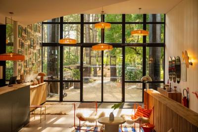 Chambre lumineuse avec lit double, rideaux rouges, balcon donnant sur un espace vert et mobilier minimaliste.
