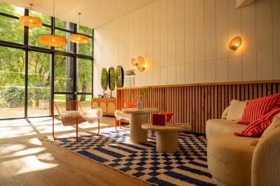 Chambre lumineuse avec lit double, rideaux rouges, balcon donnant sur un espace vert et mobilier minimaliste.