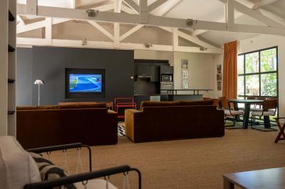 Chambre lumineuse avec lit double, rideaux rouges, balcon donnant sur un espace vert et mobilier minimaliste.