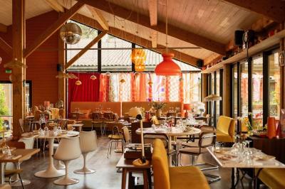 Chambre lumineuse avec lit double, rideaux rouges, balcon donnant sur un espace vert et mobilier minimaliste.