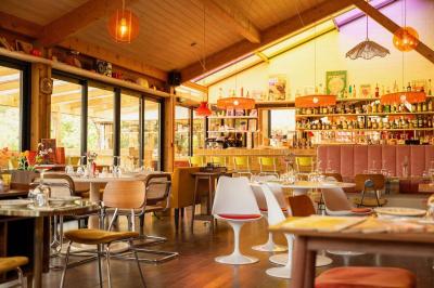 Chambre lumineuse avec lit double, rideaux rouges, balcon donnant sur un espace vert et mobilier minimaliste.