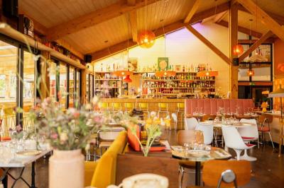 Chambre lumineuse avec lit double, rideaux rouges, balcon donnant sur un espace vert et mobilier minimaliste.