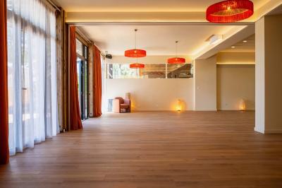 Chambre lumineuse avec lit double, rideaux rouges, balcon donnant sur un espace vert et mobilier minimaliste.