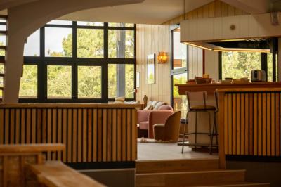 Chambre lumineuse avec lit double, rideaux rouges, balcon donnant sur un espace vert et mobilier minimaliste.