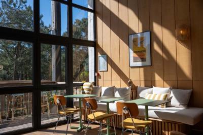 Chambre lumineuse avec lit double, rideaux rouges, balcon donnant sur un espace vert et mobilier minimaliste.
